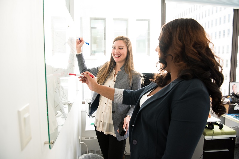 two women in front of a erase board